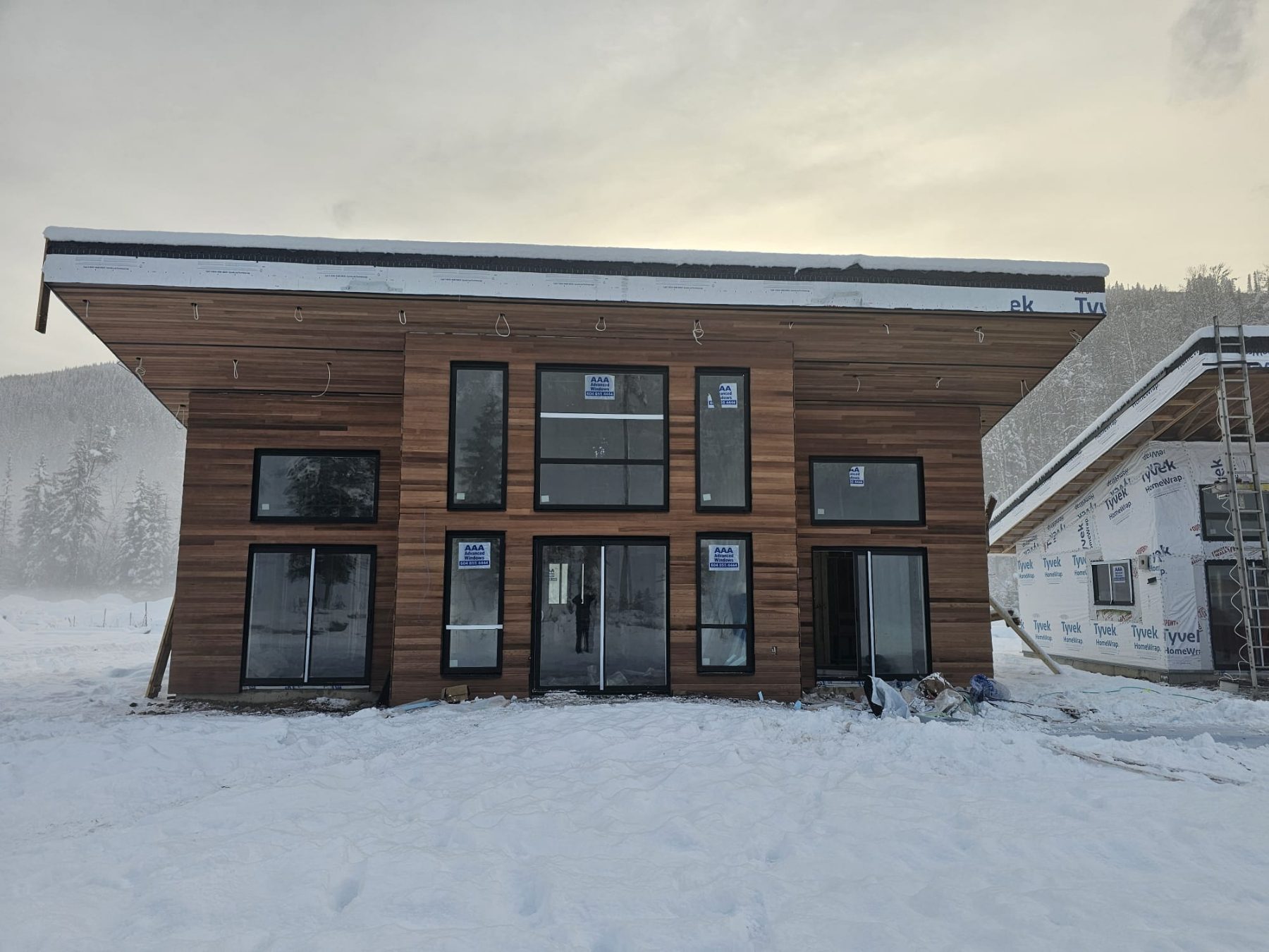 Mountain cabin clad in engineered cedar tongue-and-groove, in snow