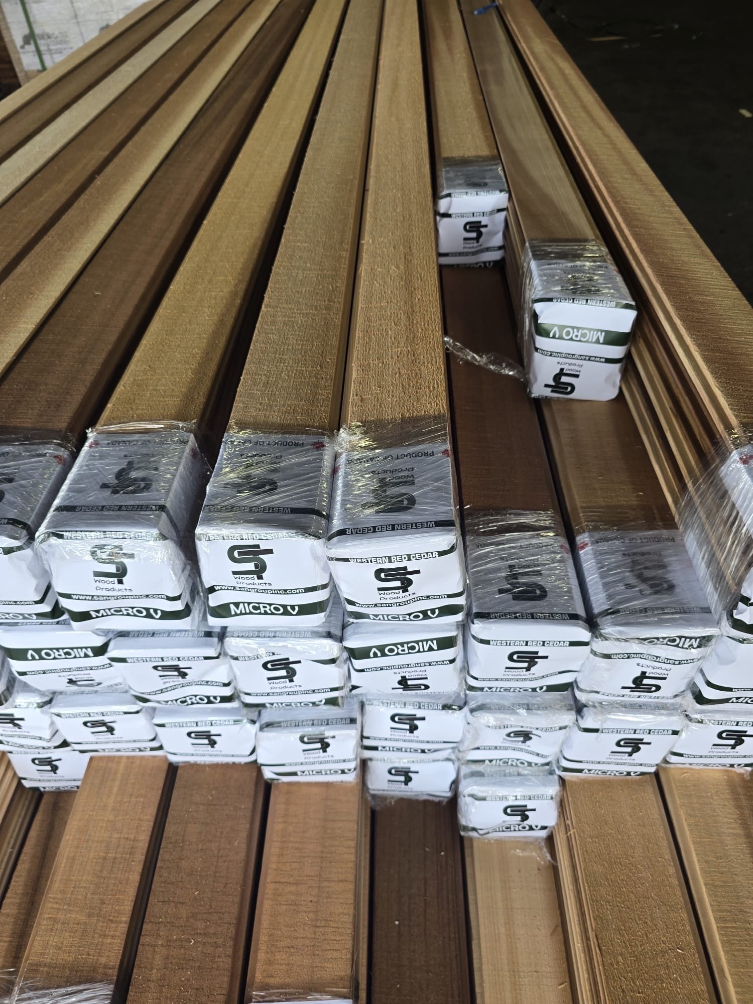 Close-up of wrapped Micro V packs of Western Red Cedar boards, with ST Wood Products end caps reading Micro V